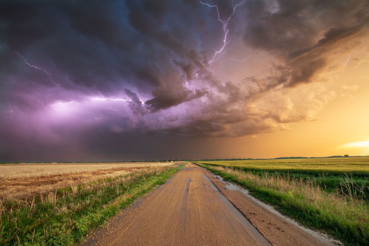 A country road stretching toward a dramatic Oklahoma sunset storm